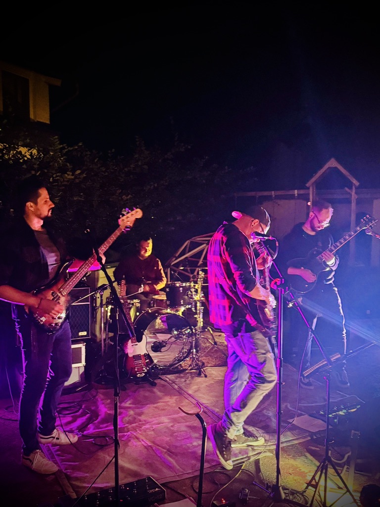 Die Band beim abendlichen Live-Auftritt mit Gitarren, Bass und Schlagzeug
